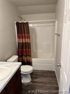 full bathroom featuring hardwood / wood-style floors, vanity, shower / tub combo with curtain, and toilet