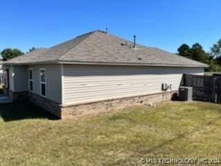 view of side of home with central AC unit and a lawn