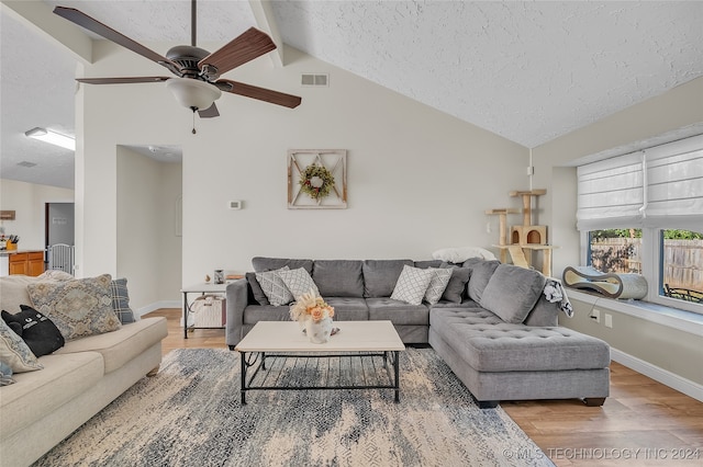 living room with a textured ceiling, beamed ceiling, high vaulted ceiling, hardwood / wood-style floors, and ceiling fan