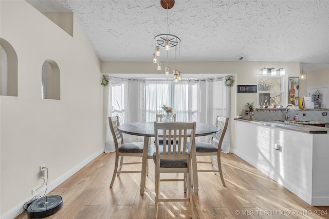 dining space with light wood-type flooring, a textured ceiling, and sink