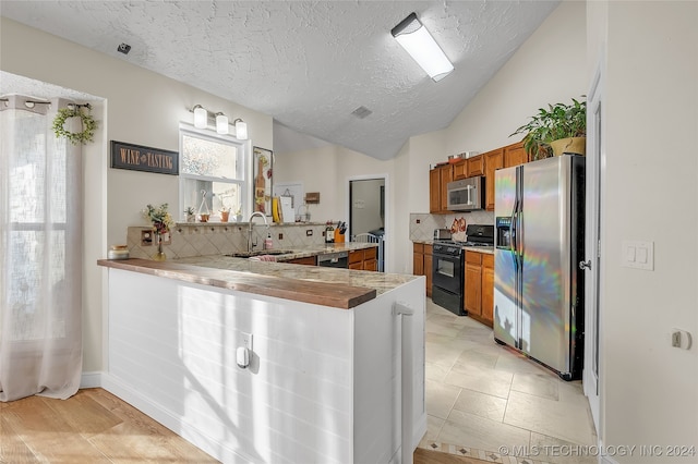 kitchen featuring a textured ceiling, black appliances, kitchen peninsula, and decorative backsplash