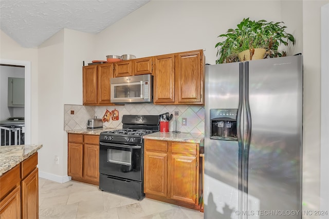 kitchen with appliances with stainless steel finishes, light tile patterned flooring, light stone counters, and tasteful backsplash