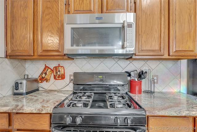 kitchen featuring light stone countertops, tasteful backsplash, and gas stove