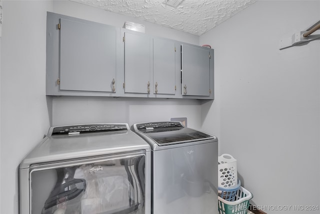 laundry area with a textured ceiling, washer and clothes dryer, and cabinets