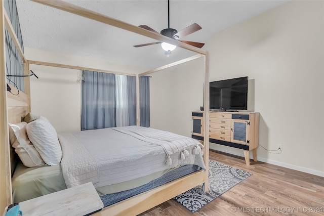 bedroom with light wood-type flooring, lofted ceiling, and ceiling fan