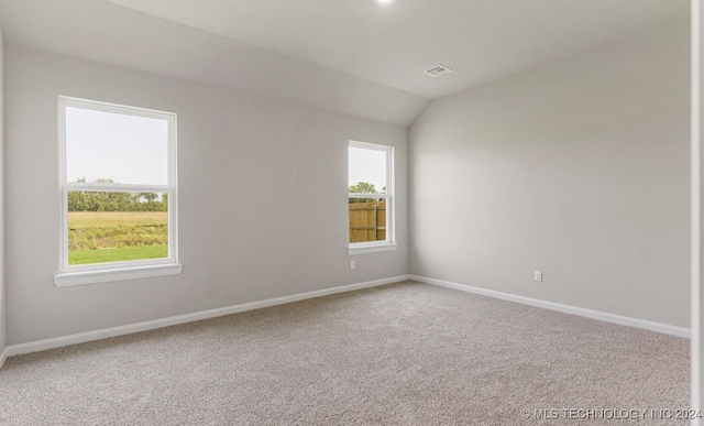 carpeted empty room featuring vaulted ceiling