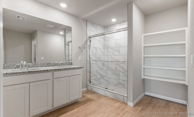 bathroom with hardwood / wood-style floors, walk in shower, and vanity