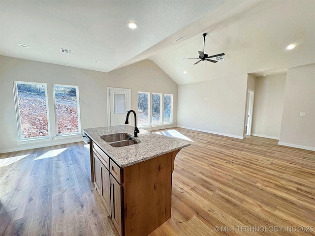 kitchen featuring light wood-type flooring, stainless steel dishwasher, open floor plan, and a sink