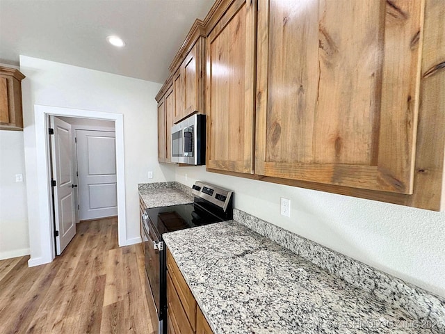 kitchen with recessed lighting, baseboards, appliances with stainless steel finishes, brown cabinets, and light wood finished floors