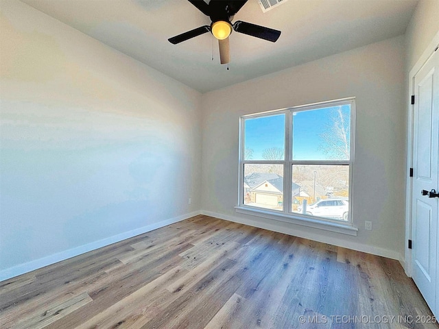 empty room featuring visible vents, wood finished floors, a ceiling fan, and baseboards