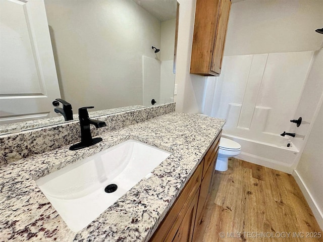 bathroom featuring shower / washtub combination, toilet, vanity, wood finished floors, and baseboards