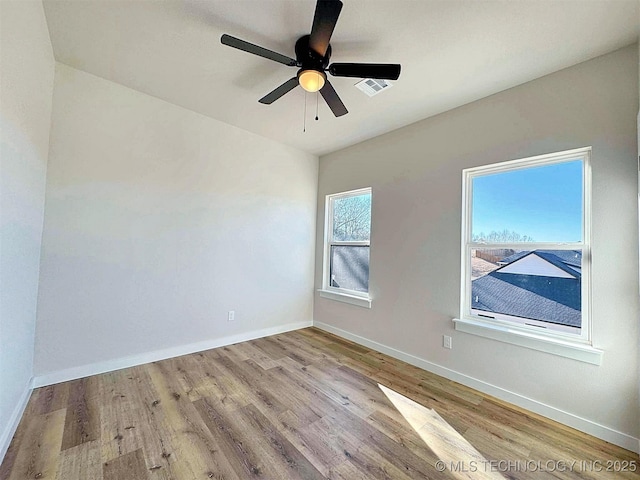 empty room featuring wood finished floors, visible vents, and baseboards