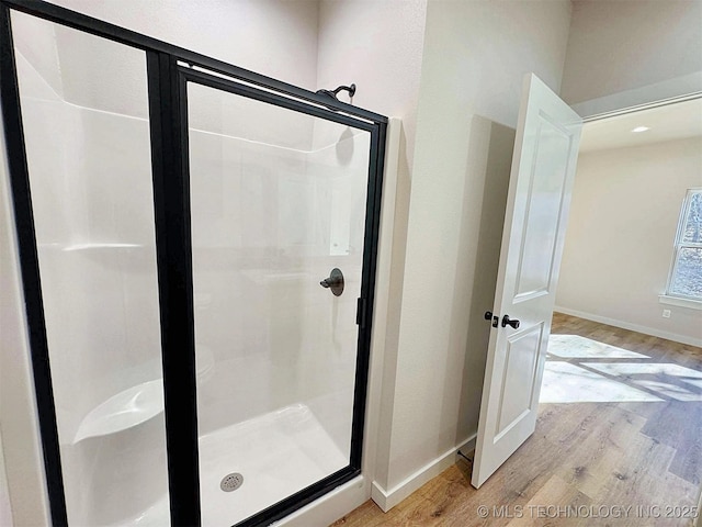 bathroom with a shower stall, baseboards, and wood finished floors