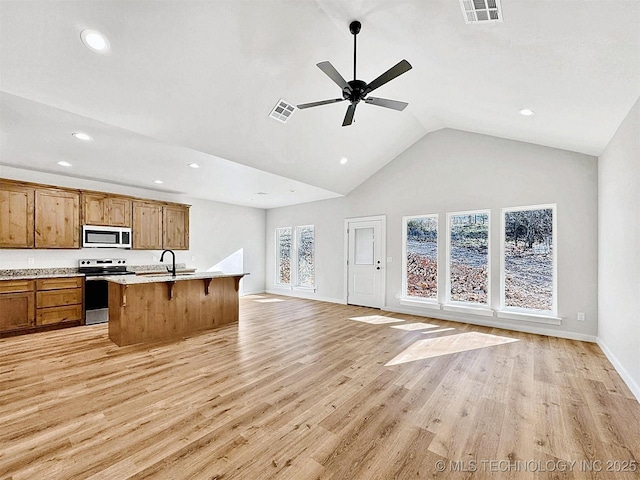 856 E Harlan Dr, Tahlequah, OK 74464 - kitchen with stainless steel appliances, open floor plan, a breakfast bar area, brown cabinetry, and recessed lighting