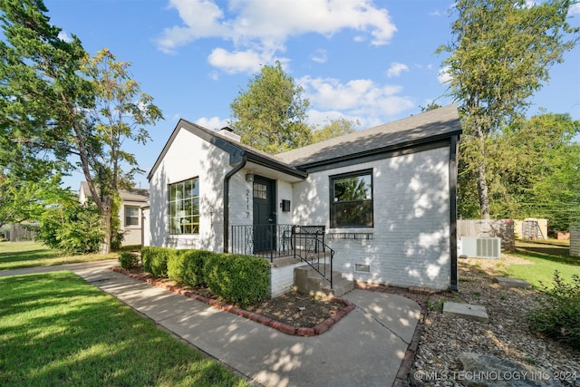 view of front of home with central AC unit and a front yard