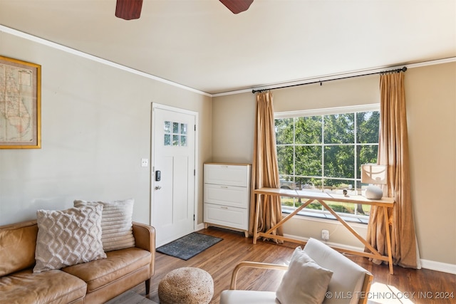 living room featuring wood-type flooring, crown molding, and ceiling fan