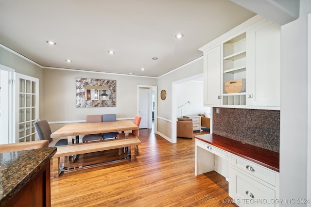 dining room featuring light wood-type flooring, built in desk, and ornamental molding