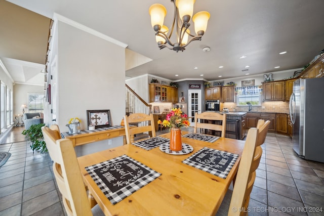 tiled dining room with ornamental molding, an inviting chandelier, and sink