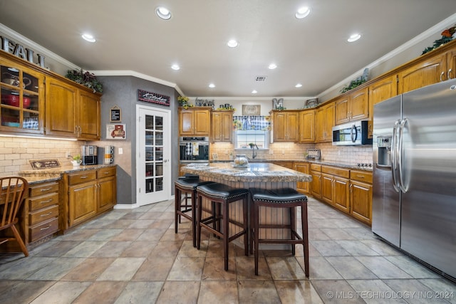 kitchen featuring a breakfast bar, a center island, appliances with stainless steel finishes, and ornamental molding