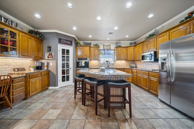 3691 E 390th Rd, Oologah, OK 74053 - kitchen with appliances with stainless steel finishes, ornamental molding, brown cabinets, backsplash, and recessed lighting