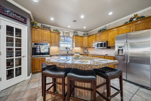 kitchen featuring stainless steel appliances, crown molding, a kitchen bar, and a center island