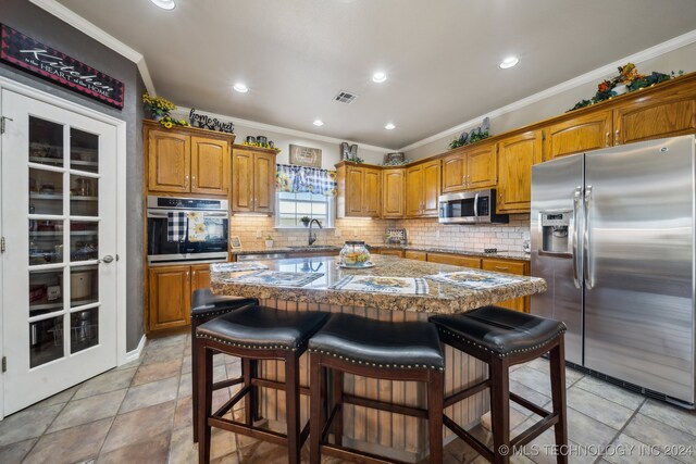 3691 E 390th Rd, Oologah, OK 74053 - kitchen featuring appliances with stainless steel finishes, crown molding, brown cabinetry, decorative backsplash, and recessed lighting