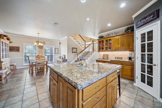 3691 E 390th Rd, Oologah, OK 74053 - kitchen with brown cabinetry, crown molding, a chandelier, tasteful backsplash, and a kitchen island
