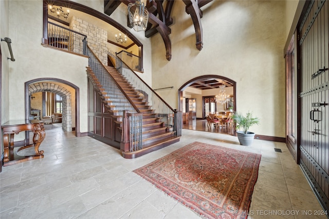 foyer featuring an inviting chandelier, a high ceiling, and beam ceiling