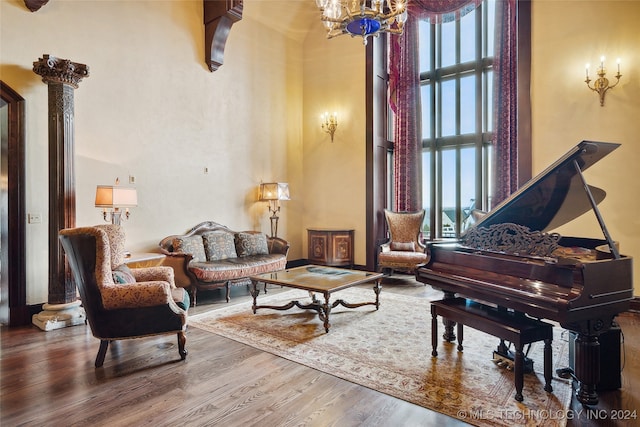 sitting room with wood-type flooring, decorative columns, a high ceiling, and a healthy amount of sunlight