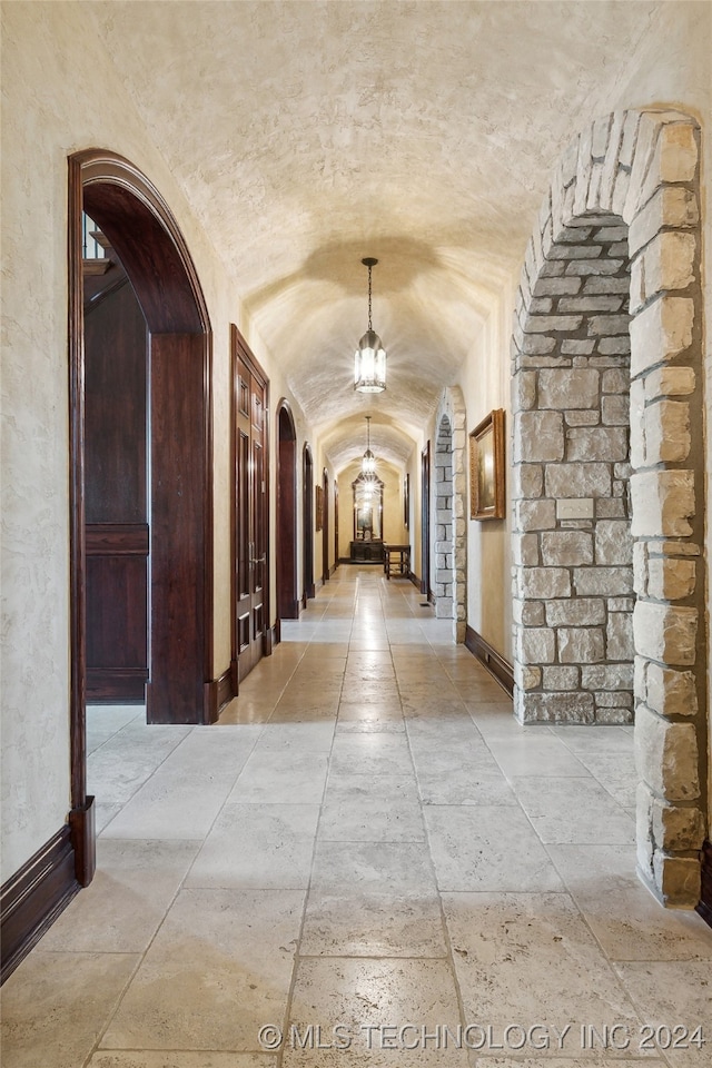 hallway with vaulted ceiling and a notable chandelier