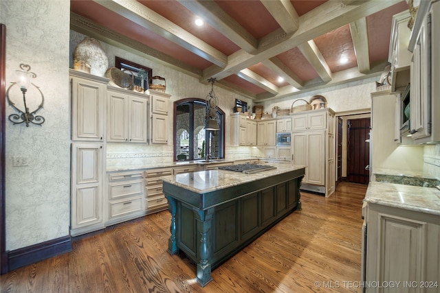 kitchen with light stone countertops, cream cabinetry, hardwood / wood-style floors, and a kitchen island