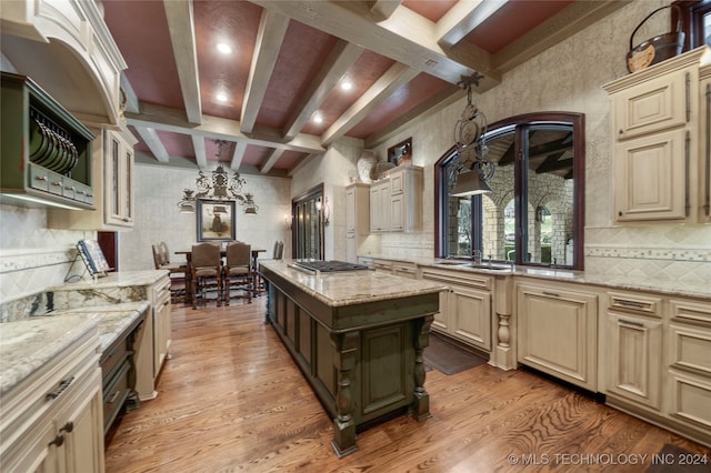 kitchen featuring beam ceiling, a kitchen island, light hardwood / wood-style flooring, cream cabinetry, and light stone countertops