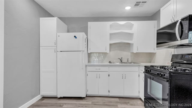 kitchen with decorative backsplash, sink, black range with gas stovetop, white refrigerator, and white cabinetry