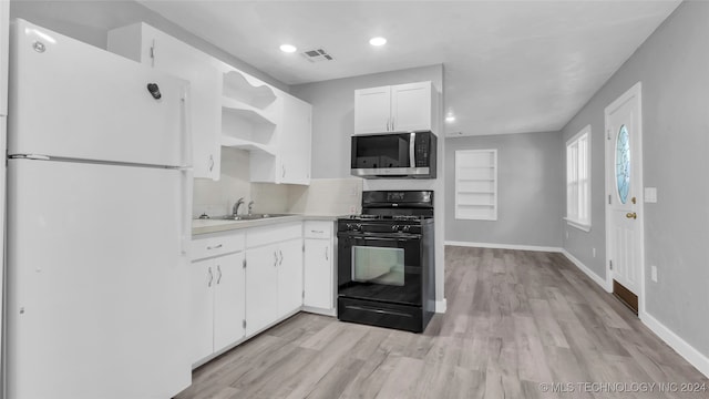 kitchen with white cabinets, white refrigerator, sink, black gas range oven, and light hardwood / wood-style floors