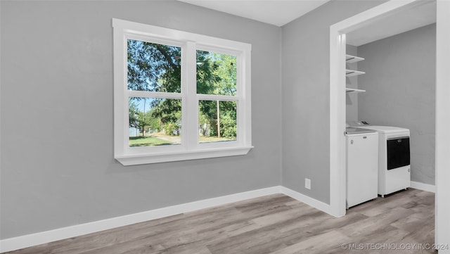 laundry room with washing machine and clothes dryer and light hardwood / wood-style flooring