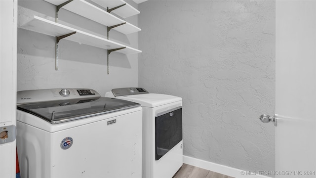 clothes washing area with washer and clothes dryer and light hardwood / wood-style floors