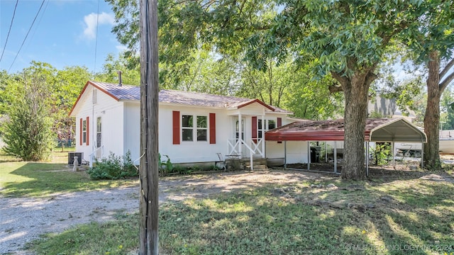 view of front of home with a carport, central AC, and a front yard