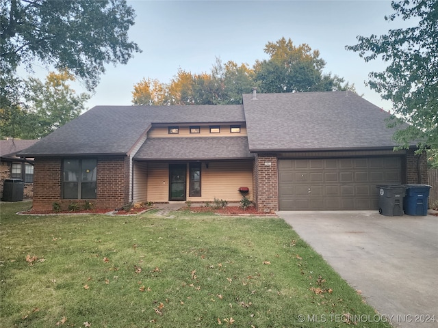 view of front of house with a garage, central AC, and a front yard