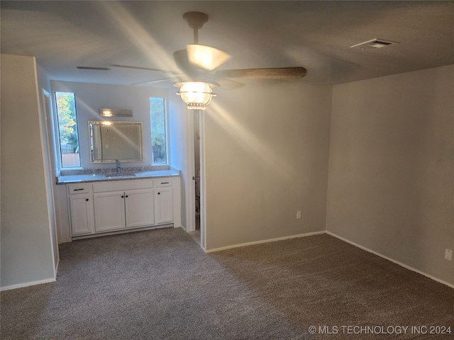 carpeted spare room featuring ceiling fan and sink