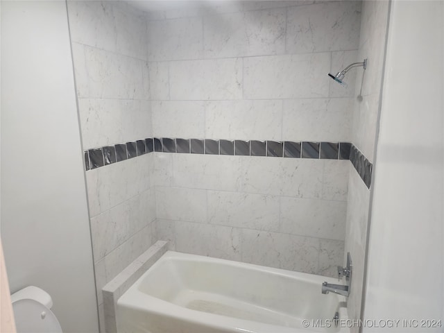 bathroom featuring tiled shower / bath combo and toilet