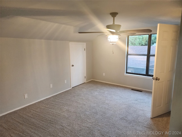 carpeted spare room featuring vaulted ceiling and ceiling fan