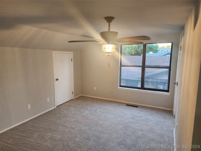 carpeted spare room featuring lofted ceiling and ceiling fan