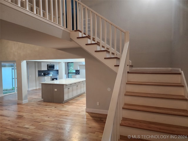 stairs featuring wood-type flooring and a high ceiling