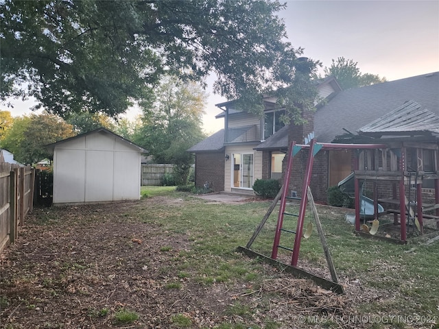 yard at dusk featuring a shed and a patio area