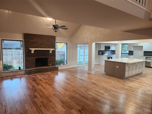 kitchen featuring white cabinets, backsplash, high vaulted ceiling, stainless steel appliances, and a center island