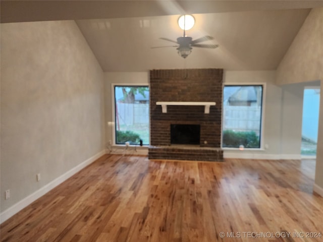 unfurnished living room with a brick fireplace, lofted ceiling, ceiling fan, and hardwood / wood-style floors