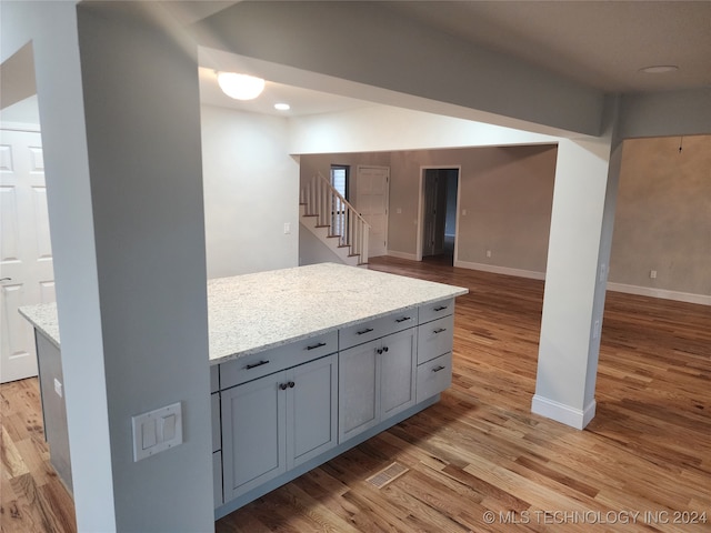 kitchen with light stone countertops, gray cabinets, and light hardwood / wood-style flooring