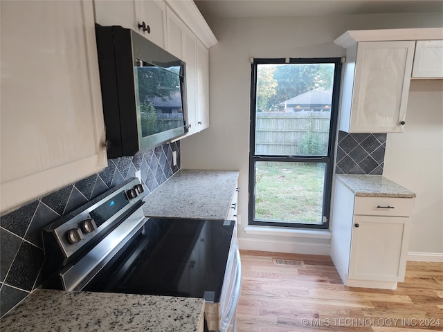 kitchen featuring white cabinets, stainless steel appliances, tasteful backsplash, and a wealth of natural light