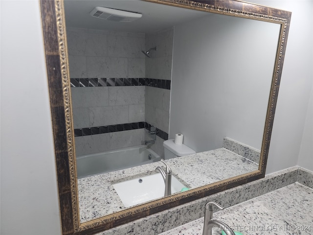 full bathroom featuring tiled shower / bath combo, vanity, and toilet