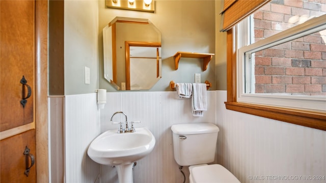 bathroom with wood walls, sink, and toilet